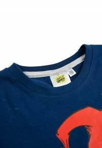 T-shirt in cotone blu con scollatura rotonda e colletto interno grigio. Presenta una grande grafica rossa. Etichetta di cura visibile all'interno della scollatura.