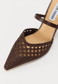 Sandale tressée marron à bout pointu avec une bride unique sur le pied et une semelle intérieure beige marquée Steve Madden.