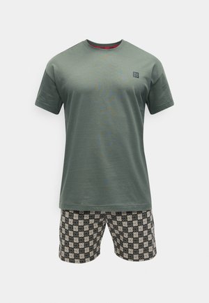 Camiseta de manga corta en verde oliva con pequeño logo en el pecho combinada con pantalones cortos negros y beige con estampado de texto repetido "HUGO".