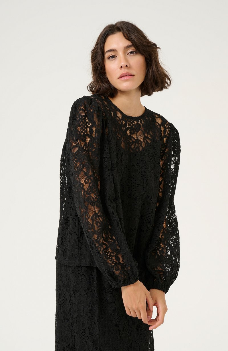 Black lace top featuring long, puffed sleeves and a round neckline. Intricate floral pattern throughout, with a slightly sheer texture.