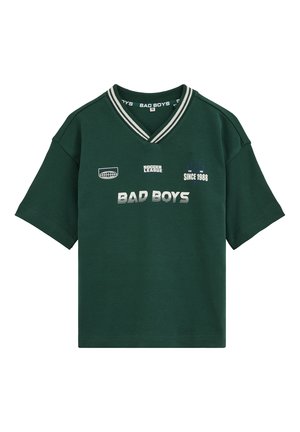 T-shirt vert foncé à manches courtes avec col en V rayé blanc et texte imprimé "BAD BOYS," "SOCCER LEAGUE," et "SINCE 1988" à l'avant.