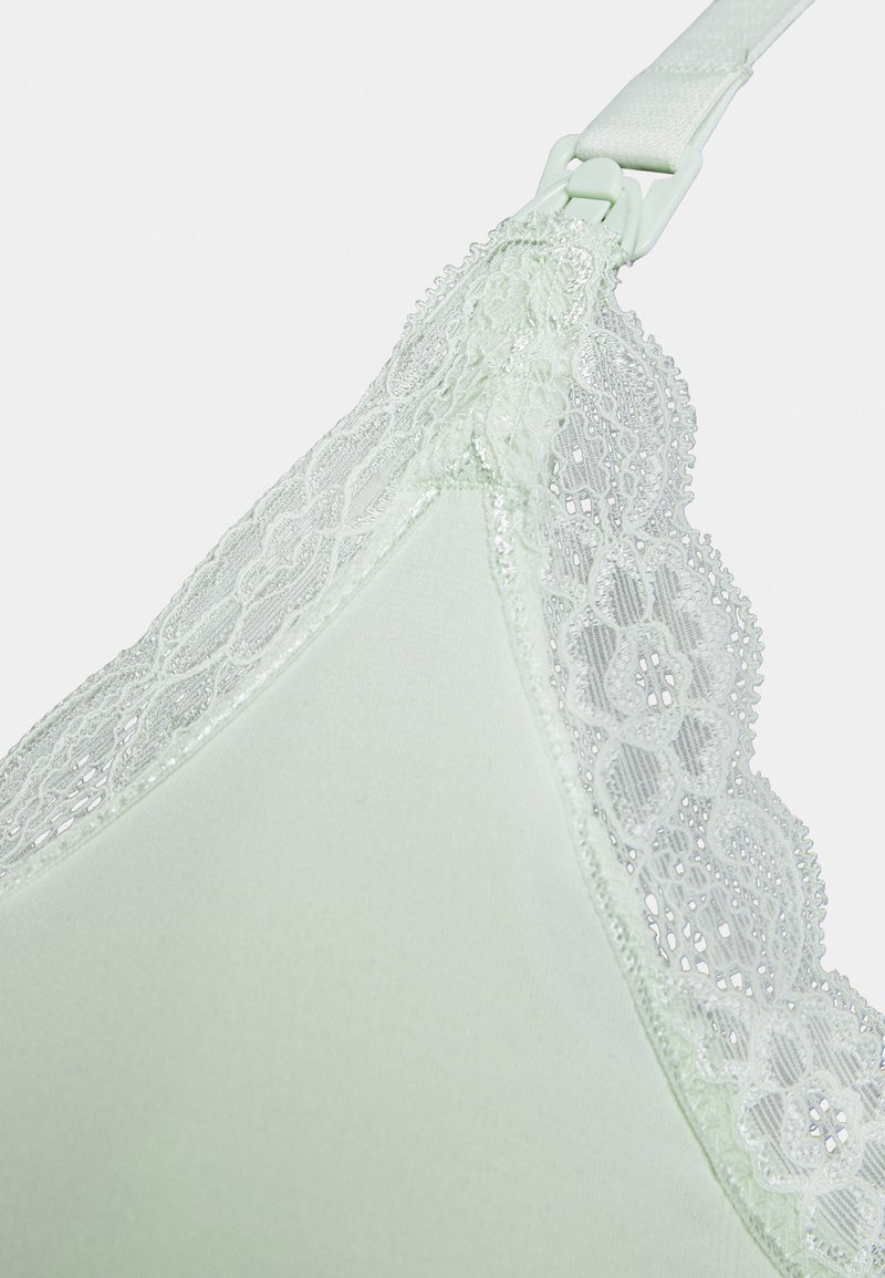 Sutiã verde-claro com renda na borda superior. O tecido liso, as alças ajustáveis e os delicados detalhes em renda floral realçam o design.