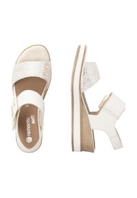 Sandales compensées blanches avec une tige texturée, une large sangle et une boucle ajustable. Semelle intérieure douce avec une semelle à texture bois et des accents légers.