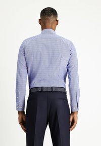  Lichtblauwe shirt met kleine, gepatterneerde stippen, lange mouwen, een traditionele kraag en witte knopen. Gepaard met donkere broek en een gepatterneerde riem.