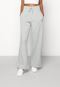 Pantalones de chándal grises de corte holgado, hechos de un tejido suave. Presentan una cintura elástica con cordón y bolsillos laterales. Pequeño logotipo en la cadera.