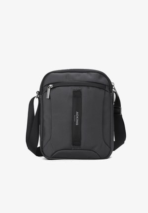 Zwarte compacte crossbodytas met verstelbare riem, voorvak met ritssluiting en verticale stoffen detail met het label "AOKING".
