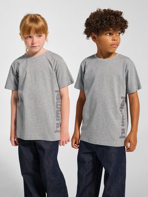 To børn står side om side iført matchende grå T-shirts med korte ærmer med lodret tekst og mørkeblå jeans mod en neutral baggrund.