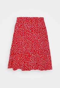 Červená sukně s nařaseným pasem, vrstveným designem a bílými puntíky. Vyrobena z lehkého materiálu, ideální pro nošení v teplém počasí.