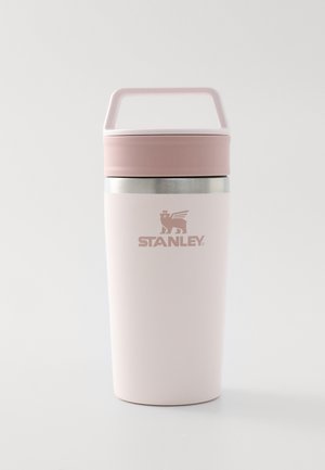 Taza de viaje aislada Stanley de color rosa pálido con asa, tapa y banda plateada cerca de la parte superior sobre un fondo blanco.