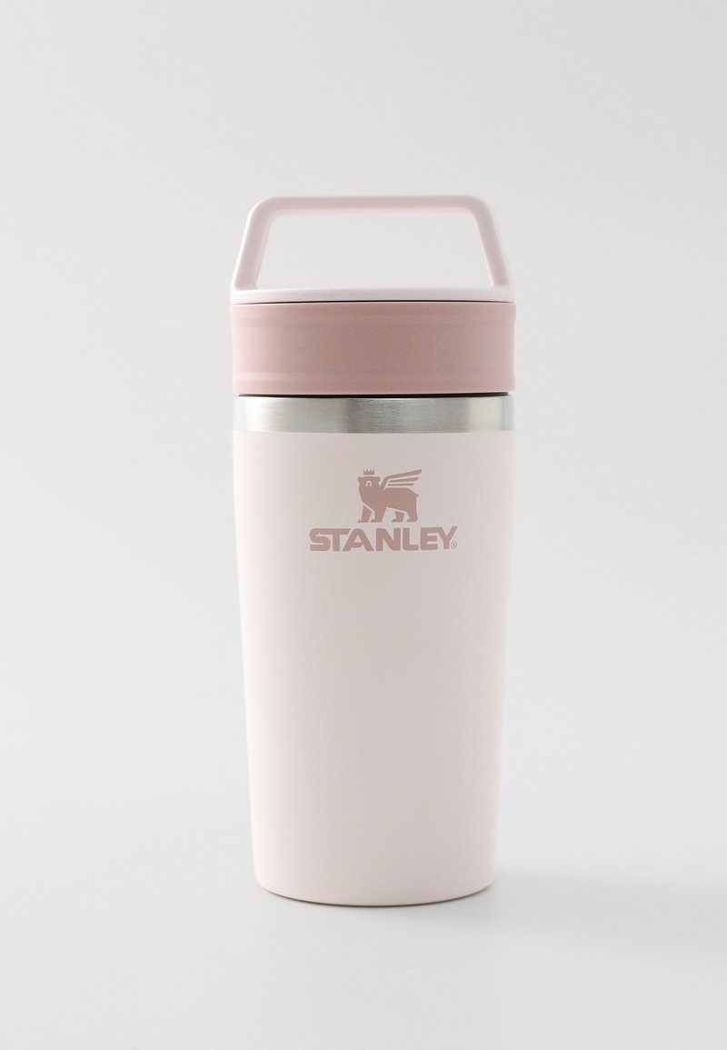 Ανιχνευτική ροζ θερμική κούπα ταξιδιού Stanley με λαβή, καπάκι και ασημί ταινία κοντά στην κορυφή σε λευκό φόντο.