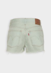 Shorts de mezclilla verde claro con un dobladillo deshilachado, dos bolsillos traseros y una etiqueta de marca de cuero en la cintura.