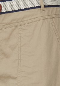 Shorts en coton beige avec poches latérales, ornés d'une ceinture texturée bleu marine et crème à rayures, avec une boucle ronde marron.
