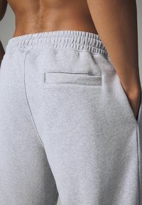 Graue Sweatpants mit einem gerippten Bund, seitlichen Taschen und einer Gesäßtasche mit rechteckigem Eingang. Hergestellt aus weichem, strukturiertem Stoff.