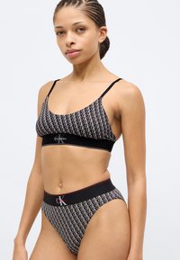 Σετ εσωρούχων Calvin Klein σε ασπρόμαυρο με γεωμετρικό σχέδιο, ρυθμιζόμενες τιράντες και αντίθετη μέση με λεπτομέρεια λογότυπου.