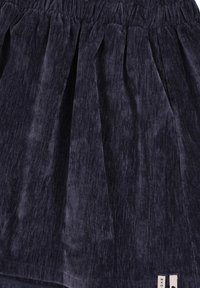 Marineblauwe fluwelen rok met een geplooide elastische tailleband, vloeiende plooien en een zachte textuur, met twee kleine labels aan de zoom.