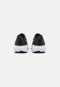 Black athletic shoes with a textured upper, featuring a white midsole and black outsole. Includes pull tabs for easy wear and reflective accents.