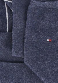 Mornarsko plava pletenina, s glatkom teksturom. Mali izvezeni logo s crvenim, bijelim i plavim detaljima u donjem desnom kutu.