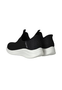 Chaussures noires à enfiler avec une tige en tricot texturé, semelle en caoutchouc blanc et design flexible. Équipées de pattes de tirage à l'arrière pour un enfilage facile.