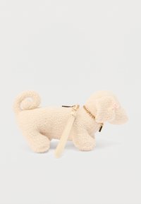 Figurine de chien en peluche couleur crème avec une queue bouclée, un collier en chaîne dorée et un petit accent en perle. Dispose d'une bandoulière amovible pour le porter.