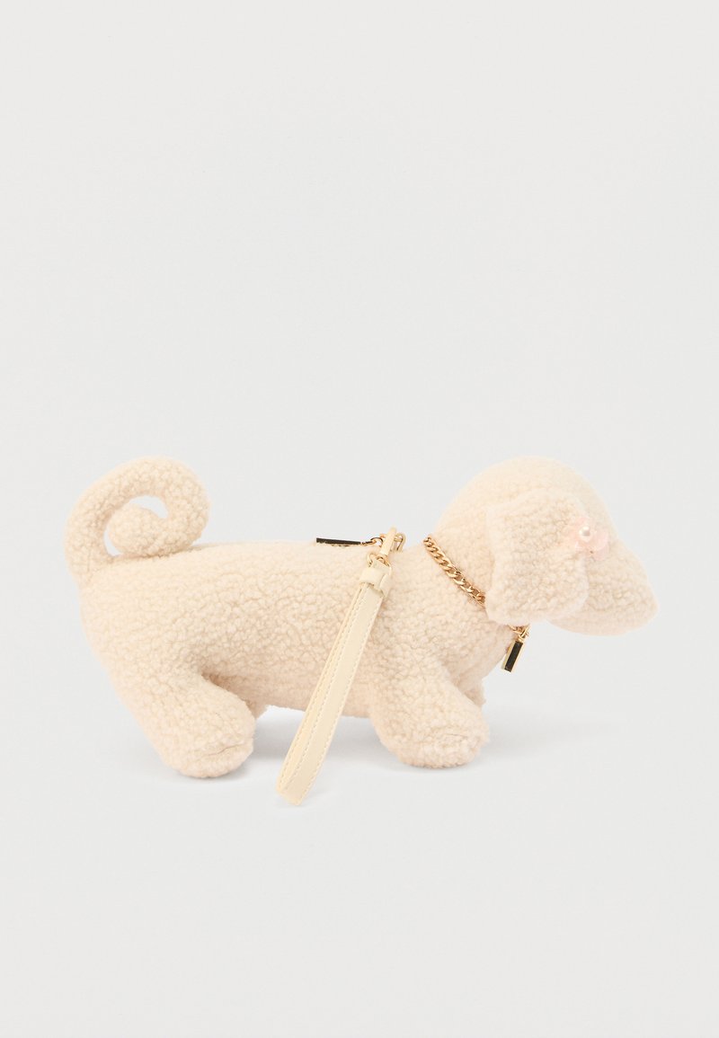Figurine de chien en peluche couleur crème avec une queue bouclée, un collier en chaîne dorée et un petit accent en perle. Dispose d'une bandoulière amovible pour le porter.