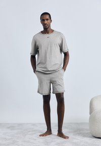 Γκρι κοντομάνικο t-shirt με στρογγυλή λαιμόκοψη και μικρό λογότυπο, συνδυασμένο με ταιριαστά γκρι σορτς. Μαλακή υφή, άνετη εφαρμογή.