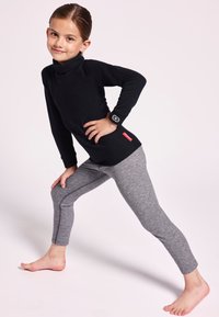 Top negro de cuello alto con una textura lisa y un diseño ajustado, combinado con leggings grises que presentan costuras laterales y un corte ceñido.