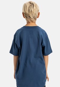 Blaues Baumwoll-T-Shirt mit lockerer Passform und kurzen Ärmeln, ausgestattet mit einem runden Ausschnitt und einer glatten, gleichmäßigen Oberfläche.