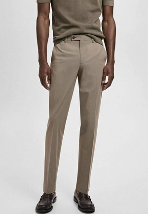 Beige tailored trousers with a slim fit, made from a smooth material. Features a concealed zipper, side pockets, and back welt pockets.