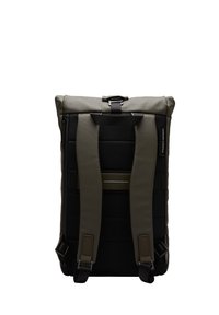 Sac à dos au design rectangulaire, fabriqué en tissu résistant. Présente un dessus vert olive, des côtés noirs, deux bretelles rembourrées et ajustables, ainsi qu'une fermeture par boucle.
