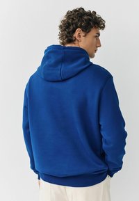 Blauer Kapuzenpulli mit großer verstellbarer Kapuze, gerippten Bündchen und Saum. Weicher Stoff, schlichtes Design ohne sichtbare Muster oder Akzente.