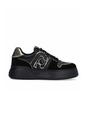 Sneaker nera con una combinazione di pelle liscia e camoscio, dettagli metallici sul tallone e sul logo, e suola in gomma testurizzata.