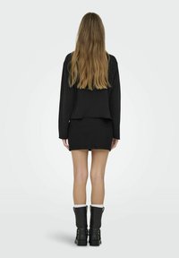 Un hanorac scurt negru, o fustă mini din denim negru, cizme negre până la genunchi cu accente albe. Textură netedă, design simplu și fără modele vizibile.