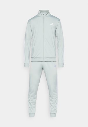 Lichtgroene trainingsoutfit met een ritsjack en bijpassende broek. Bevat witte zijstrepen en een Adidas-logo op de bovenste linkerborst en bovenbeen.