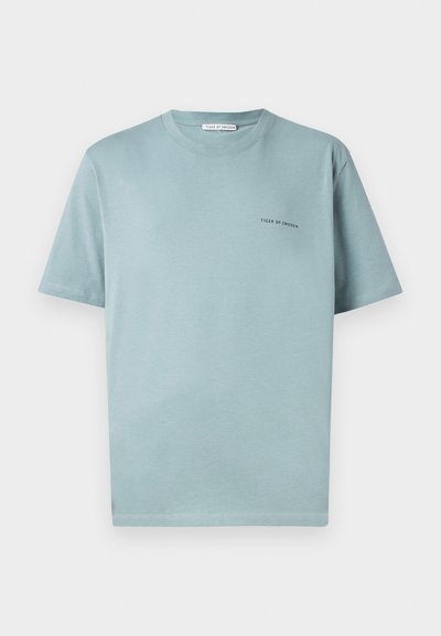 Světle modré bavlněné tričko s kulatým výstřihem, krátkými rukávy a malým logem "TIGER OF SWEDEN" na levé straně hrudi. Hladká struktura.