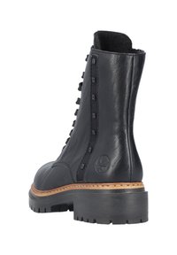 Bottines noires en cuir avec lacets, dotées d'une finition texturée, de clous carrés sur le côté et d'une semelle en caoutchouc épaisse avec un léger talon.