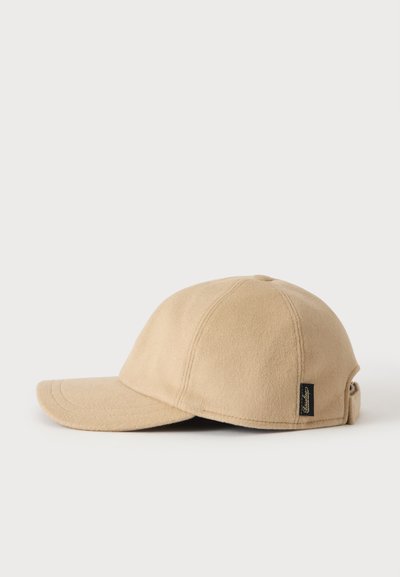 Casquette de baseball beige avec une visière courbée, tissu doux, coutures visibles et une petite étiquette de marque noire sur le côté.