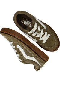 Zapatillas de lona marrón con acentos blancos, suela plana de goma, punta redonda y cierre con cordones. Superficie texturizada y cuello acolchado.