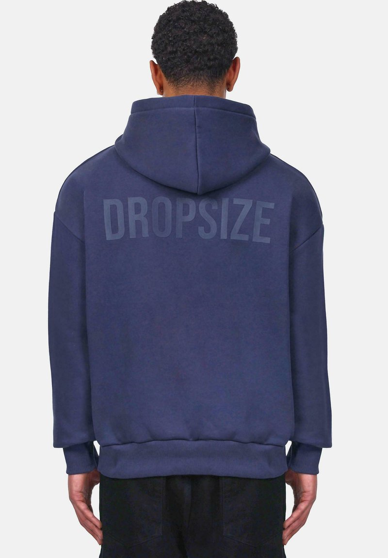Tummansininen huppari, jonka takana on suuri "DROPSIZE"-printti. Siinä on naruilla säädettävä huppu, ribbireunukset ja rento istuvuus. Pehmeä kankaan rakenne.