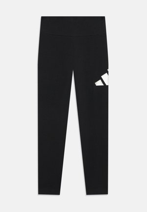 Leggings pretos feitos de tecido elástico, com uma cintura larga e um logo geométrico branco na coxa esquerda. Textura suave.