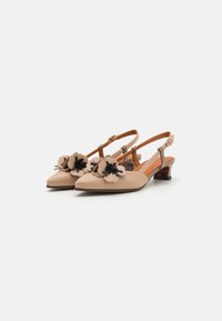 Chaussures à brides en cuir beige avec des bouts pointus et un petit talon, ornées d'accents floraux en crème et noir, conçues avec une sangle à boucle.
