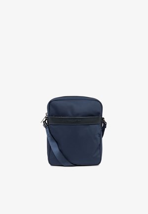 Sac bandoulière bleu marine en nylon résistant, avec une bandoulière amovible et un accent en cuir noir sur le devant avec détail du logo.