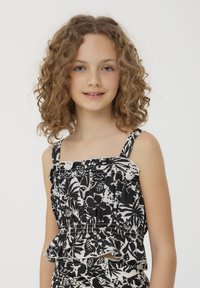 Top floreale in bianco e nero con sottili spalline, tessuto arricciato e orlo arricciato. Il materiale sembra leggero e traspirante.