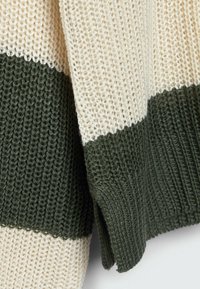 Knit sweater featuring alternating horizontal stripes of cream and dark green. Textured fabric with a loose weave and side slits.