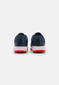 Navy sports shoes with red rubber treads, white midsole, textured synthetic material, and padded collar, designed for traction and comfort.