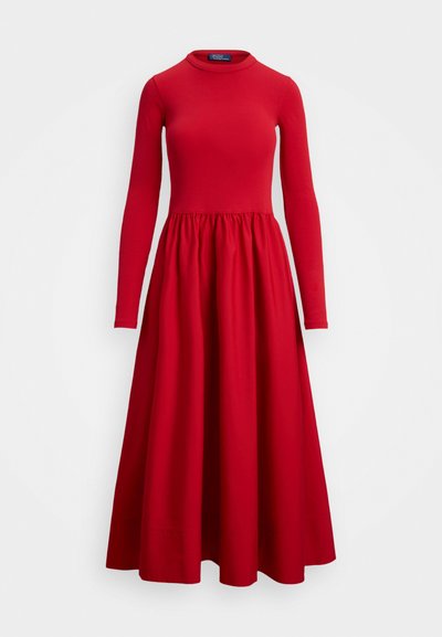 Dolga rdeča obleka z okroglim izrezom, prilegajočim zgornjim delom in razširjenim krilom. Narejena iz raztegljivega blaga; guban detajl v pasu.