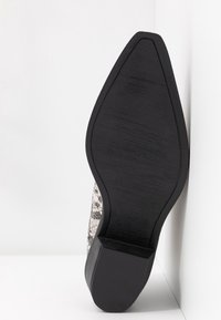 Spitz zulaufender Schuh mit Schlangenlederstruktur in Schwarz- und Grautönen. Verfügt über eine schwarze Gummisohle mit einem leichten Absatz und der Größenangabe "37".