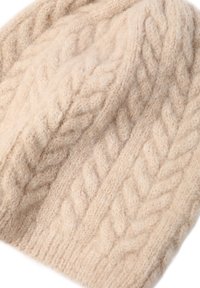 Beige neulepipo, joka on valmistettu pehmeästä villasta. Pipo on paksussa letkutikannassa ja siinä on tekstuuri. Muoto on pyöreä ja se istuu mukavasti.