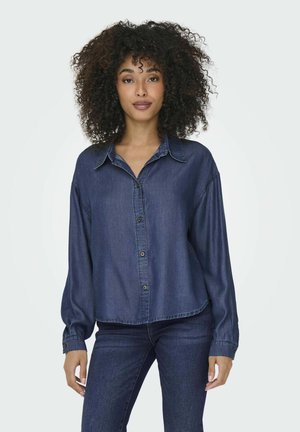 Camicia di denim blu scuro con collo a detergente, chiusura con bottoni e vestibilità comoda. Maniche lunghe con polsini abbottonati e dettagli di cucitura discreti.