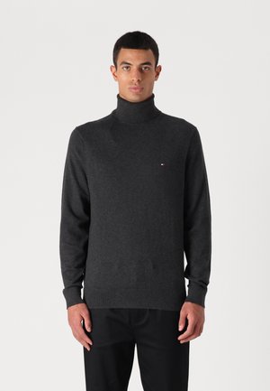 Suéter de cuello vuelto gris oscuro hecho de una tela suave, con un diseño ajustado, mangas largas y un pequeño logo en el pecho.