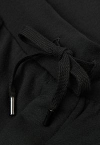 Zwarte trainingsbroek met een gestructureerd trekkoord met metalen aglets, gemaakt van gladde stof en een elastische tailleband voor extra comfort.